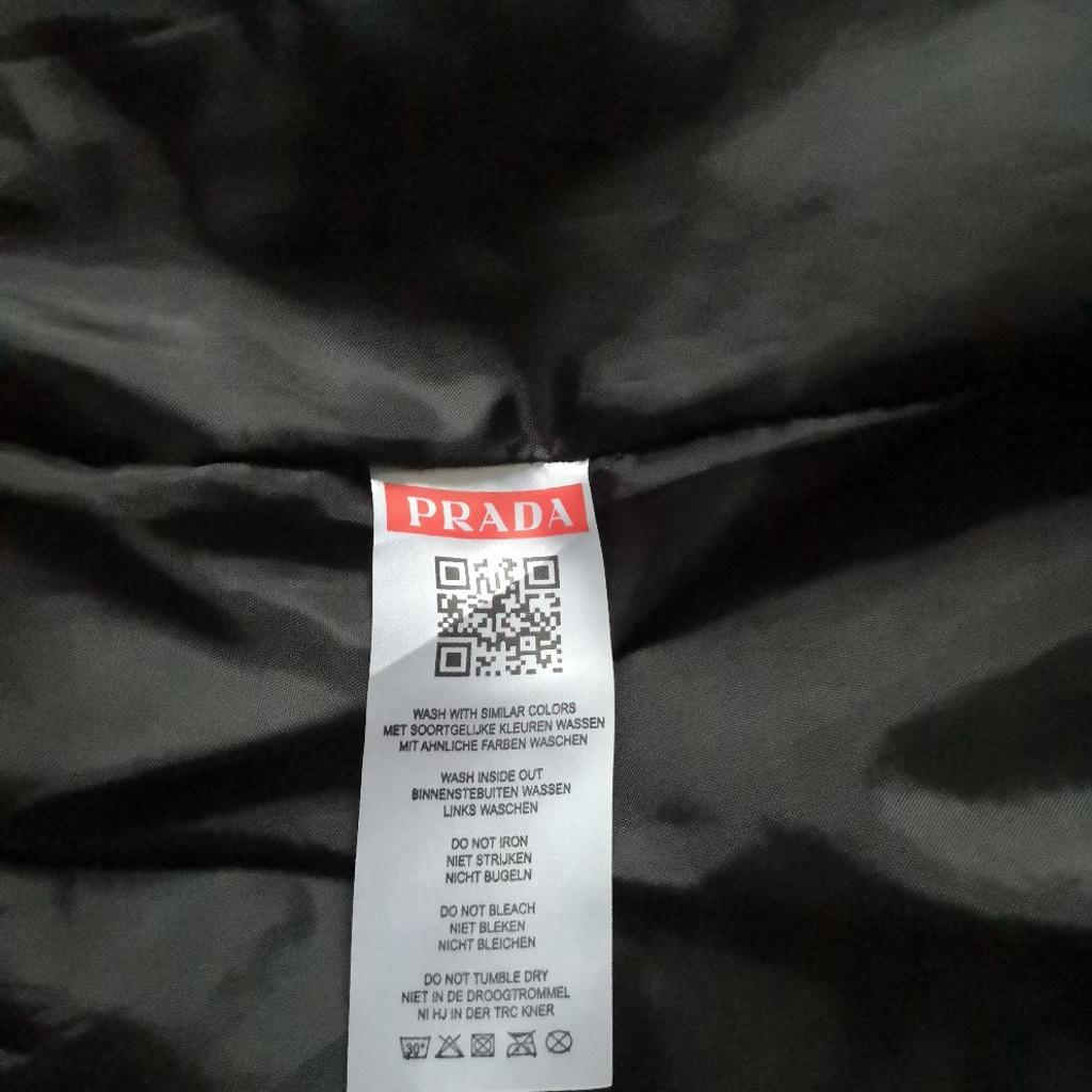 Prada Hooded Bomber Style Outdoor Rain Jacket. Brand new with tag. Size XXL, but would also fits XL. 2 Zipped side pockets, 1 zipped breast pocket, 1 zipped arm pocket and pouch. Lightweight, not padded or quilted. Selling due to car purchase, cash needed! Excellent quality and value compared to original price! Collection preferred, as too valuable for posting and buyer must try on for size and satisfaction. However, I'm prepared to post via insured, tracked and signed for postage at extra cost of £20. Must sell, hence asking such a low bargain price of £195, which is significantly lower than the true value of this item!