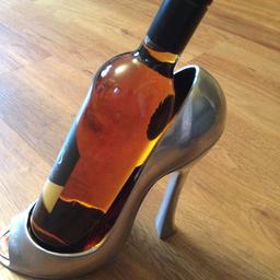 Metal wine bottle holder shaped as a woman’s shoe. with red glossy lining. Unusual present. Approximately 22cm x 22cm tall. Very good condition. Collection only please.