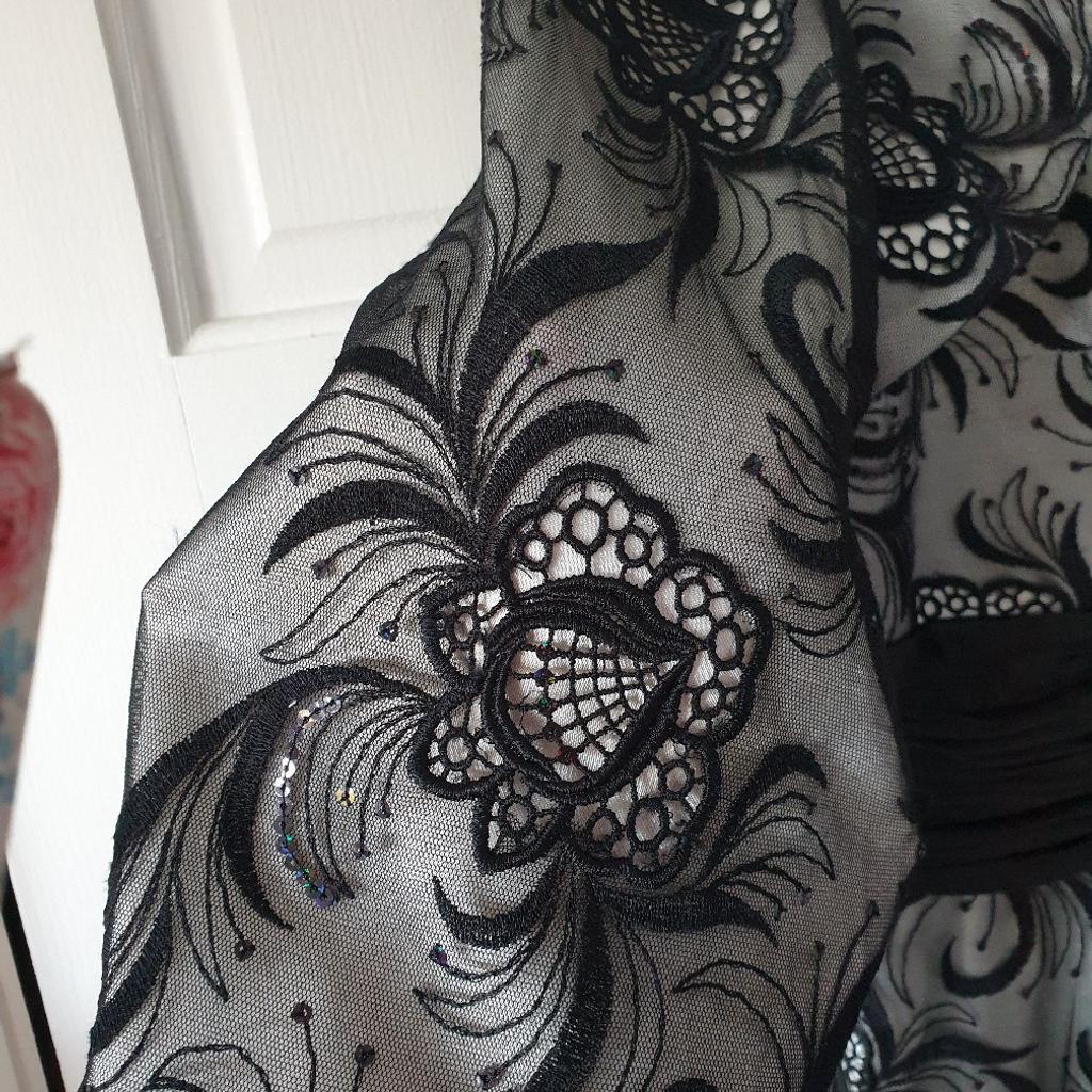 A gorgeous 2 piece black lace maxi dress with floral patterns & delicate sequins scattered all over. Has a matching pretty lace jacket. A UK Size 16 but can fit size 18 too as the back is adjustable with extra space & material and ribbon ties. The dress was purchased from a boutique in Hertfordshire by Dynasty London. The dress hem has a delicate fishtail design & falls beautifully with a slimming shape.

Rarely worn so in excellent condition.

For collection or can be posted.

Good offers will be considered.