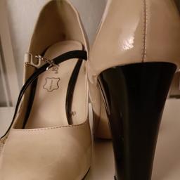 Mary Jane style leather shoes in a neutral beige with black heels and trim.
