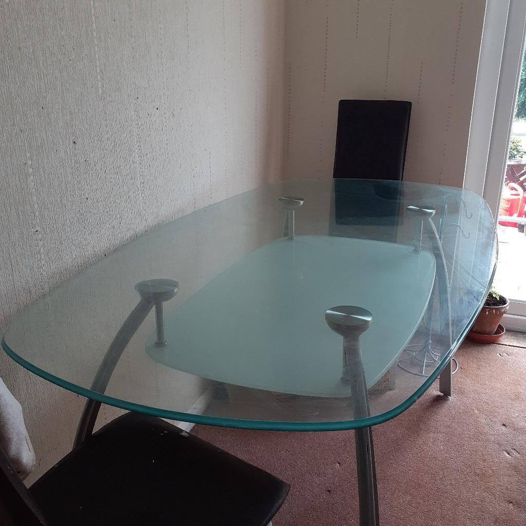glass dining table and 4 high backed black chairs. the table has silver legs. and glass top and a frosted shelf no longer eanted