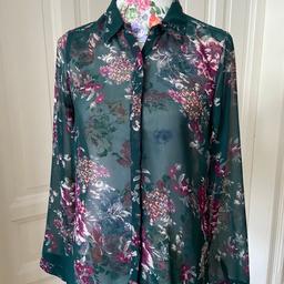 Transparente Bluse von vero moda, dunkelgrün, mit Blumenmuster in Lila&Pastell. Mit Kragen. Verdeckte Knopfleiste vorne. Größe ist mit M angegeben. Schulterbreite 38 cm, Länge 55 cm.
