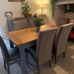 Solid oak table with grey painted legs and 6 leather seat chairs with grey fabric back excellent condition used a couple of times buyer to collect