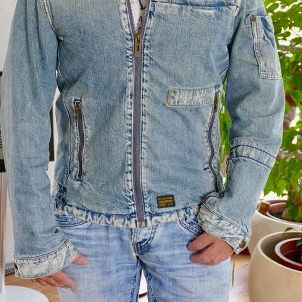 1 sportlich geschnittene Unisex Jeansjacke von G-Star in der Gr. L/52. Die Jacke mit lässigem Stehkragen und Druckknöpfen hat 2 seitliche Taschen mit Reißverschlüssen und 1 aufgesetzte Brusttasche.