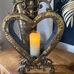 HERE I HAVE A HEART SHAPED ORNATE METAL CANDLE HOLDER. ( FAUX CANDLES ONLY). VERY ORNATE DISTRESSED GOLD. REALLY HEAVY METAL . GLASS TO THE BACK OF THE HOLDER BUT NOT TO THE FRONT. POP A BATTERY OPERATED CANDLE IN TO IT. MAKES A REAL STATEMENT WHEREVER YOU PLACE IT. MEASURING 18 INCHES IN HEIGHT & 10 INCHES IN WIDTH. COLLECTION OR CAN DELIVER LOCALLY FOR FUEL.