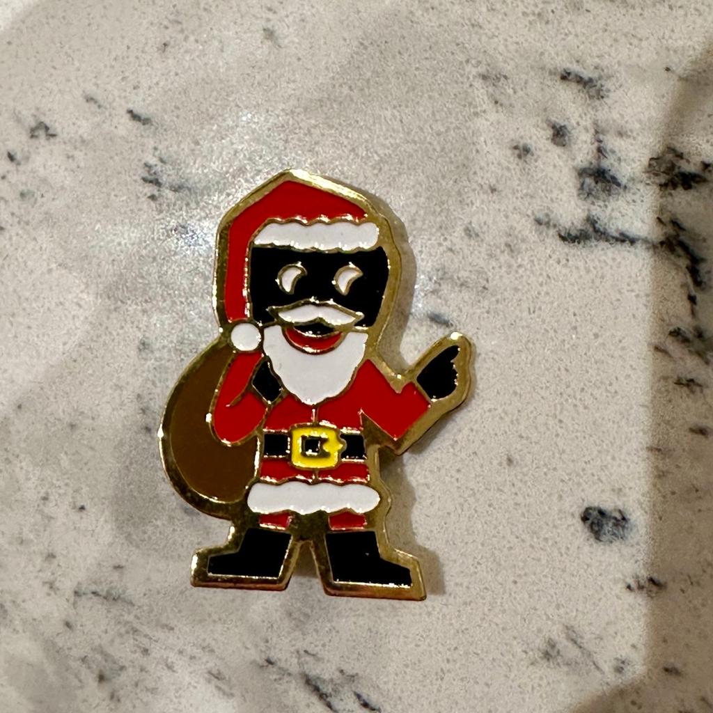 A scarce original circa 1990's 'Robertson's Golly Father Christmas limited edition badge', the reverse impressed with multi maker's details ' © James Robertson & Sons'. Good condition, complete with original pin fittings with safety roller catch in good working order.
Robertson's Father Christmas Golly badge was issued in 1990 as a limited edition of 2400, available to staff only. It was used to help to raise money for the 'Cancer Research Campaign'. However a later issue of 850 was made available in 2002, a year after Golly's retirement.