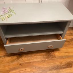 This is a up cycled TV stand. The legs have been shorted so that you can sit on to take your shoes off or put on. It is ideal for a busy hall space. Store shoes in it hats and scarfs. It has been painted grey and decorated with a transfer.
89 cm L x 36 cm D x 52 cm H