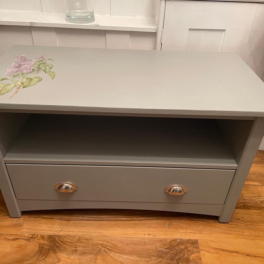 This is a up cycled TV stand. The legs have been shorted so that you can sit on to take your shoes off or put on. It is ideal for a busy hall space. Store shoes in it hats and scarfs. It has been painted grey and decorated with a transfer.
89 cm L x 36 cm D x 52 cm H