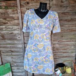 Vintage 1990s retro mini tea dress. White background with pastel blues, purples, greens, and mustard yellow floral patterns. Short A-line shape skirt. Ruched chest cups. Short sleeves with inverted pleat sides. V-neck. Zip up back. Fully lined in white fabric. 
Possibly handmade. Slight stretch. 
Approximate size 10.
Chest measures 34"-36"
Waist measures 32"
Hips measure 38"-40"
Length 34.5"