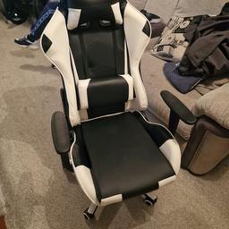 This black and white gaming chair has a high back and padded headrest, padded seat, armrests and comes with a head and back pillow.