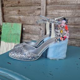 Asos design size 6 chunky heeled shoes. Rounded toe. Covered heel. Adjustable buckle ankle strap.  Silver insole. Covered in irridescent silver glitter. Heel embellished with colourful 3d beaded gem plastic flowers. Block heel covered in baby blue faux fur.
Insoles have a few dents. Worn a couple of times so marks on soles....see pics.