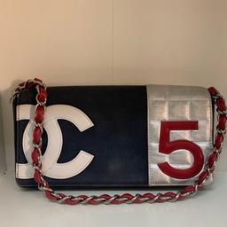 Tracollina Chanel originale, con codice interno, modello No 5, in tela blu navy con inserti in pelle argentata, logo CC bianco e 5 rosso. Catenella argentata con pelle rossa all interno.
Tasca interna con chiusura zip. Interno argentato.
Misura 25cm x 20cm circa.