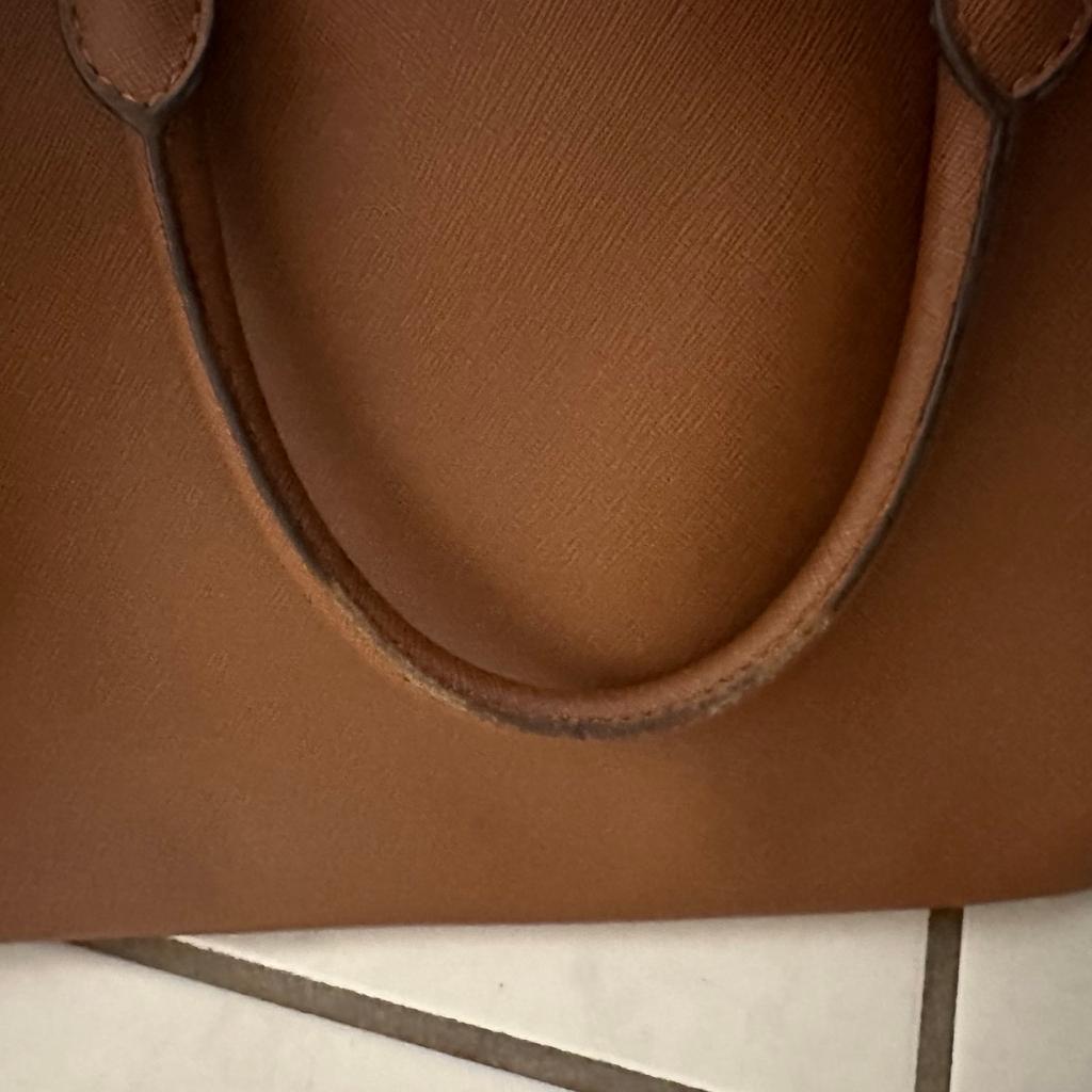 Benutzte Michael Kors Original Handtasche in Cognac Farbe mit unbenutzten Schulterträgern.
Gebrauchsspuren am Griff auf der Innenseite zu erkennen und die Tasche knickt auf einer Seite leicht ein.

Maße:
Breite: 33 cm
Höhe: 25 cm
Tiefe: 15 cm ( unten an der breitesten Stelle)

Privatverkauf: keine Gewährleistung oder Garantie.