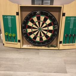 Dart board in cabinet with 3 sets of darts.

Board is still in good condition. Marking on front from tape used to hold door shut.

Collect only.