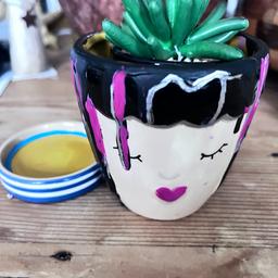 Hand-painted ceramic little planter including saucer and faux cacti in its own little pot. 

This little lady has dark hair, sleepy lashes, and a pretty pink pout. 
She is painted with frenchic paint with drips of colour. this planterthe mantelpiece in a quirky living room. 
A gorgeous little gift at a special price till Sunday for mothers day ( usually £15)
One only 

Dimensions
planter - width (at widest point) 8.3cm x height 8.2cm x depth 8.3cm
tray - width 6.8cm x height 1.6cm x depth 6.8cm
full height (with planter in tray) 9cm