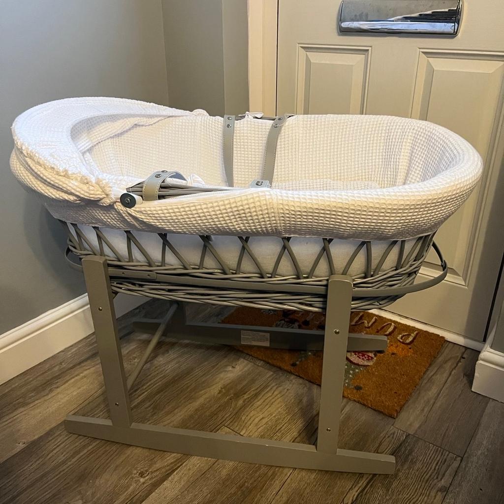 Grey Moses basket with white bedding. Rocking stand