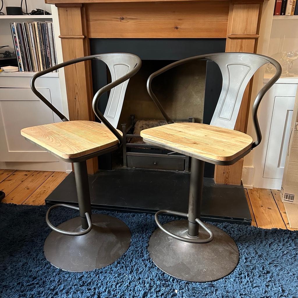Two identical industrial style bar stools with adjustable heights. Oak wooden seats and metal frames. In great condition, no marks or scratches. Original packaging not available.