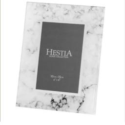 Display your cherished memories in style with this stunning Hestia Home Collection photo frame. The rectangular frame features a beautiful white marble effect with marbled pattern that will complement any home decor.

Measuring 10cm x 15cm (this is the photo area, not the actual frame dimensions) this portrait-oriented photo frame is perfect for holding a 4" x 6" photograph. Crafted from high-quality glass material, this photo frame not only adds elegance to your living space but also provides longevity. Ideal for any room in your home, this Hestia Home Collection photo frame is a perfect addition to your photo display collection.

Please note: This frame is freestanding only and NOT suitable for hanging on wall.