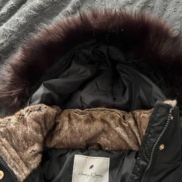 Woman’s black padded fashionable coat with brown fur on collar and hood . Size 10 from Debenhams . Black with gold zips on pockets .