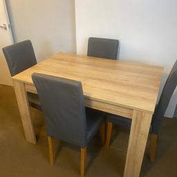 Elegant oak dining table set in brown and dark grey. This stylish set includes a sturdy wood table and matching chairs, all in good condition. Perfect for family meals or entertaining guests.