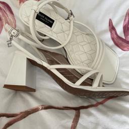 Worn once. Lovely condition. White straps sandals with ankle fastening. RI charm hanging from ankle strap. Chunky heel. Wide fitting. Size 6