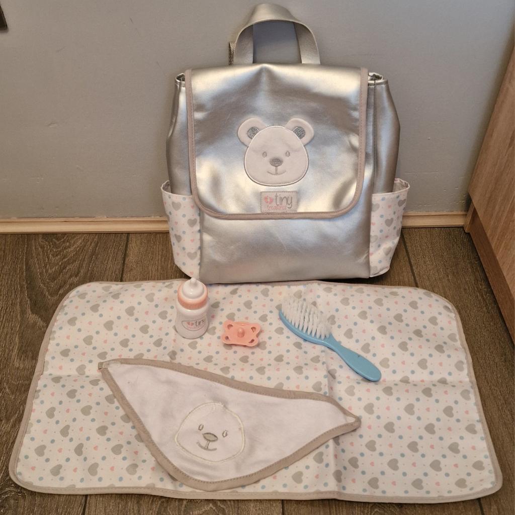 Tiny Treasures Baby Doll Changing Bag 
Suitable for 17 inch (44cm) height dolls.
Includes Rucksack, bottle, changing mat, bib, hair brush, dummy.
Size H29.1, W27.3, D7.7cm.
Collection ls12
