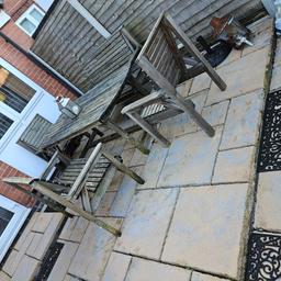 large outdoor wooden table with 2 large chairs and 2 benches with padded covers