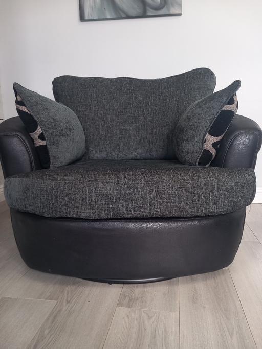  — Grey swivel chair with 2 patterned pillows.
